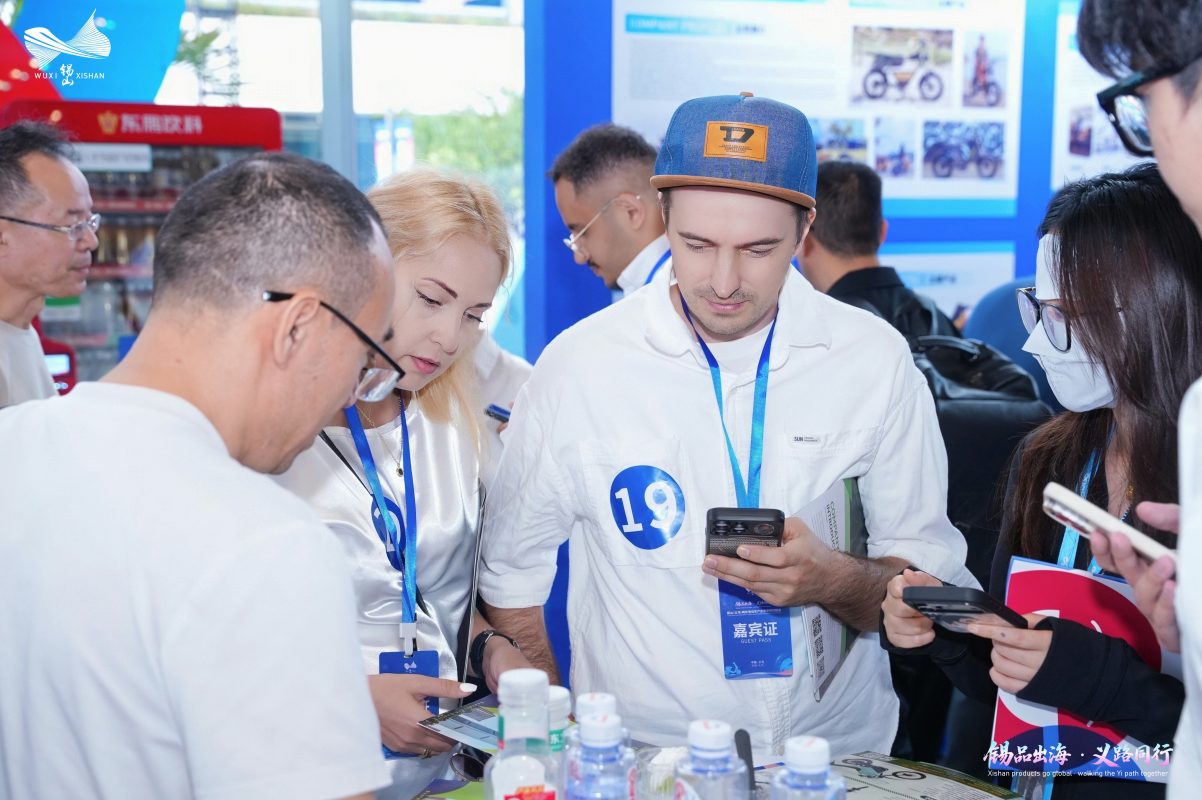 Overseas buyers discuss product information with a Xishan supplier at a crowded table.