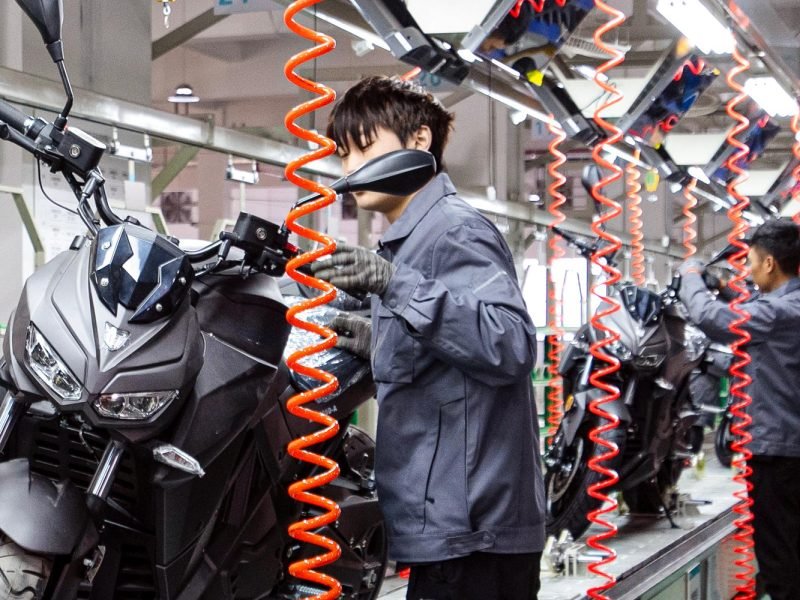 Nooma motorcycle assembly line with workers assembling new motorcycles.